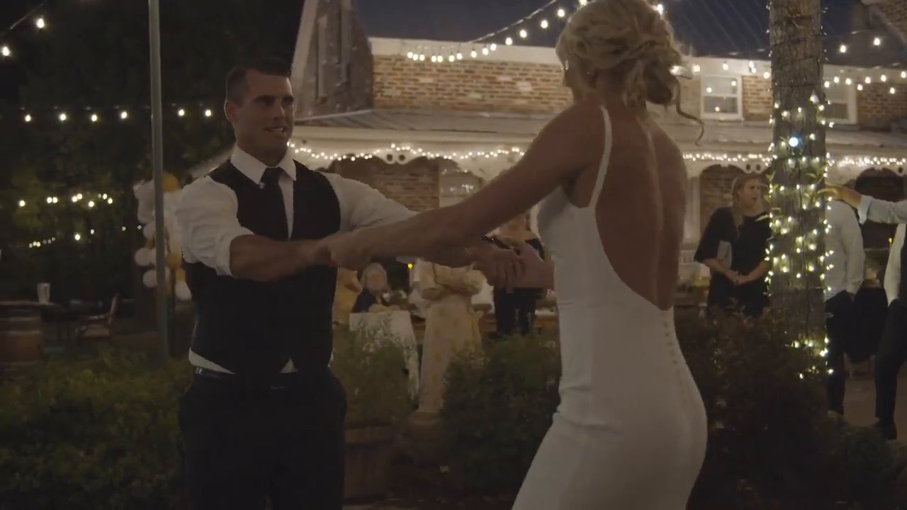 Nicole and Tim dance in front of the lit porch.