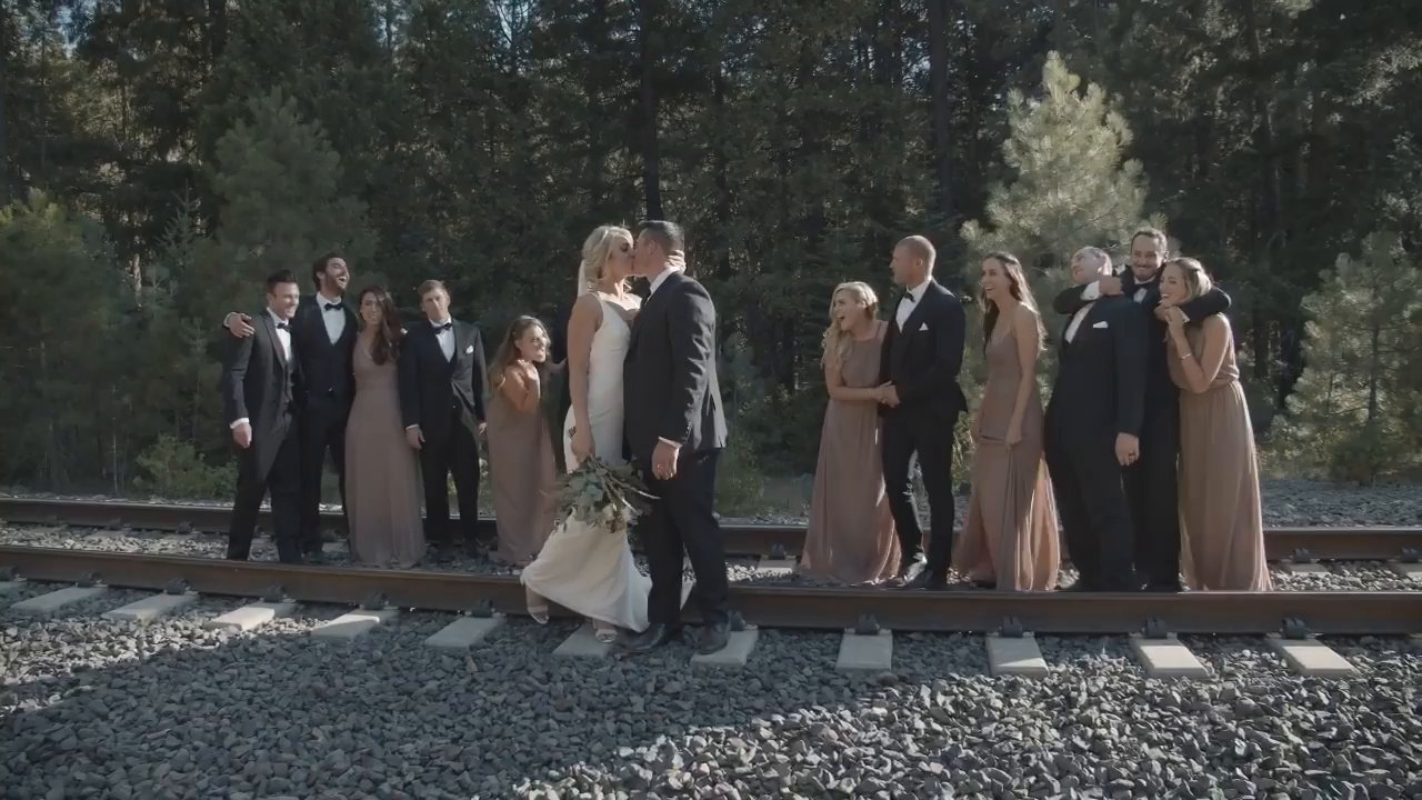 The whole wedding party stands on the railroad tracks with Nicole and Tim.