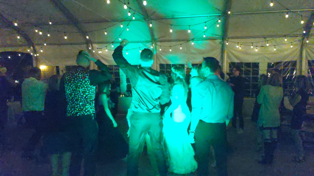 Guests throw their hands up on a green lit dance floor at Sunridge Golf and Recreation