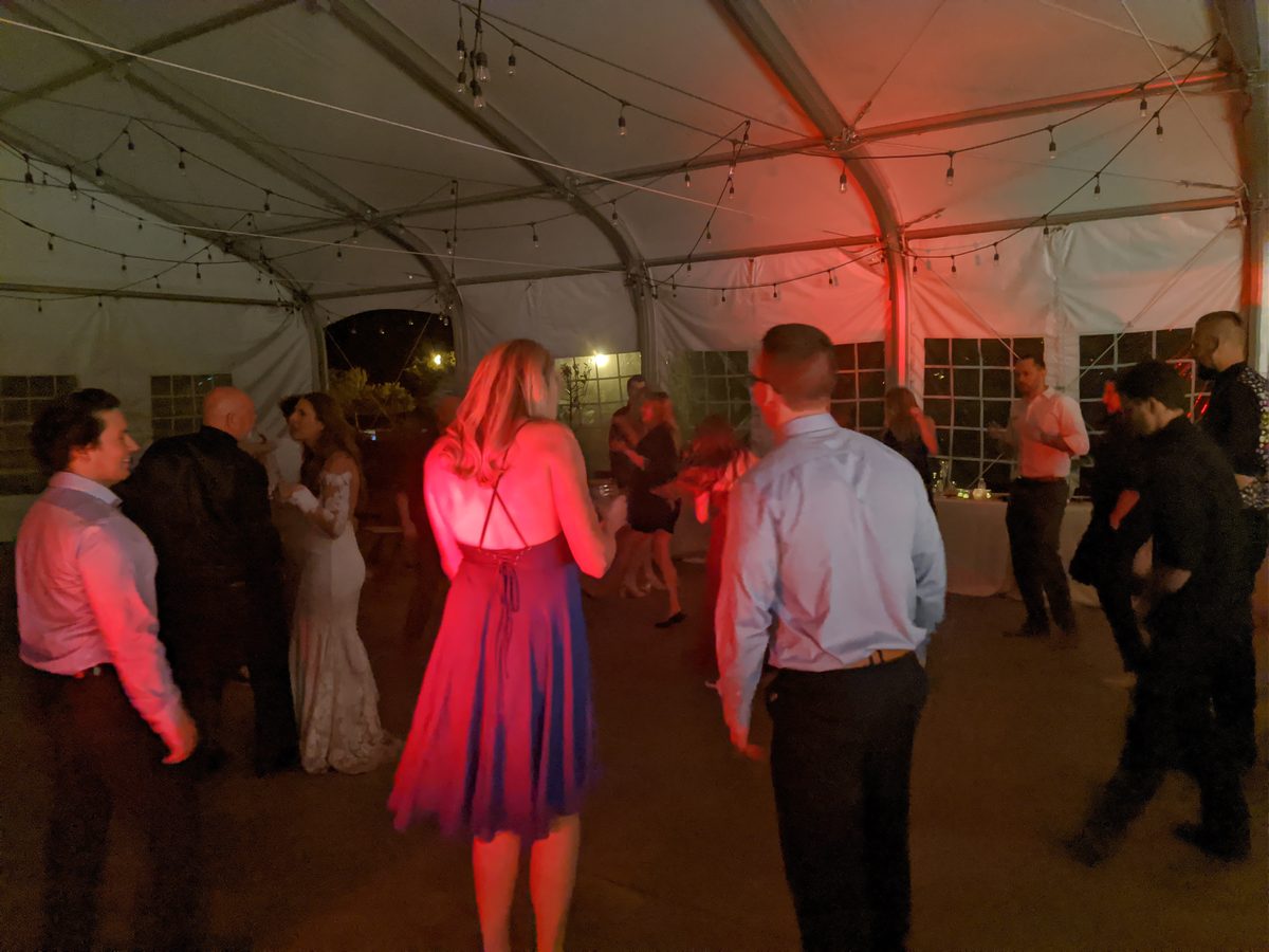 A guest in a red skirt spins on the dance floor under warm pink light at Rachel and Christopher's wedding