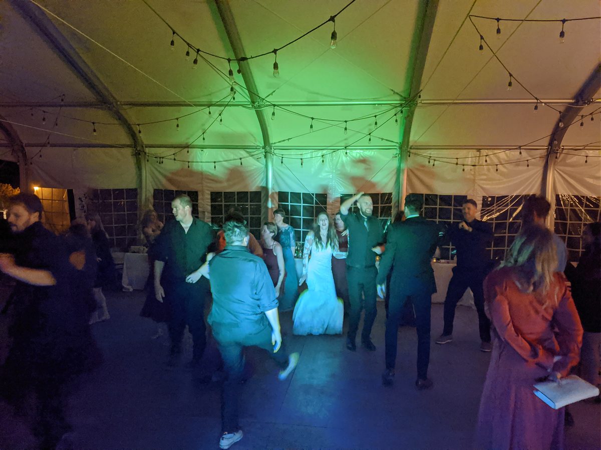 The whole tent dances together under green light and string lights at Sunridge Golf and Recreation