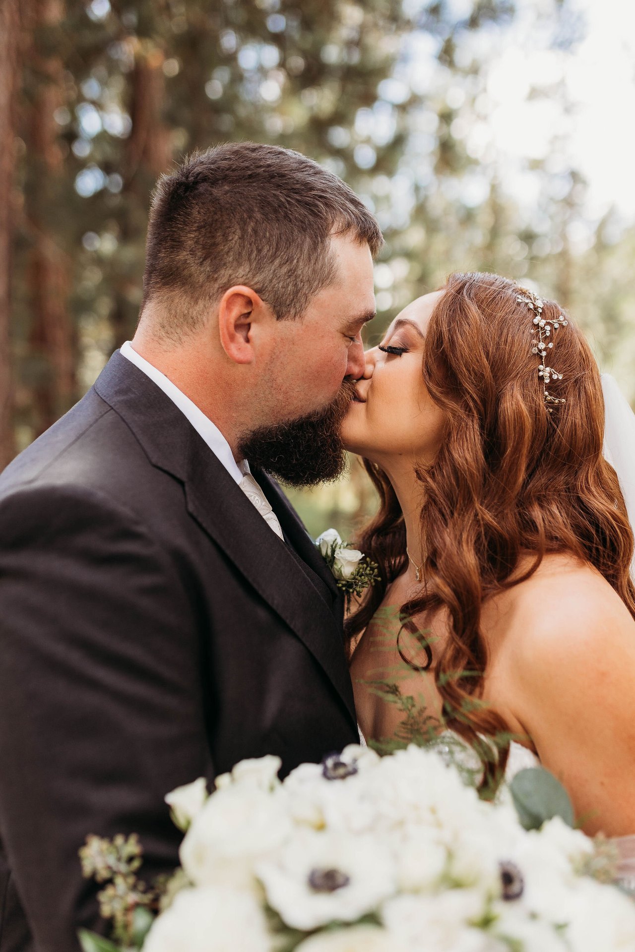Remy and Tom share a kiss close up behind her bouquet