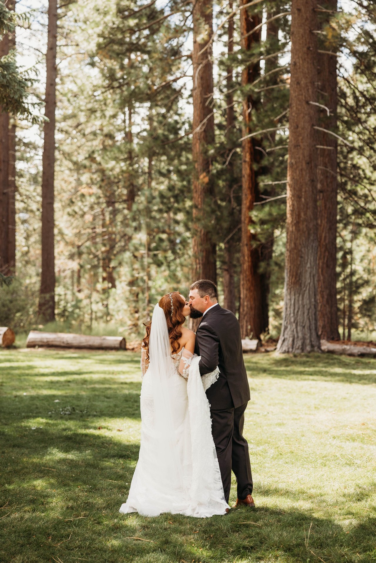 Tom kisses Remy on the lawn beneath the tall pines at Valhalla