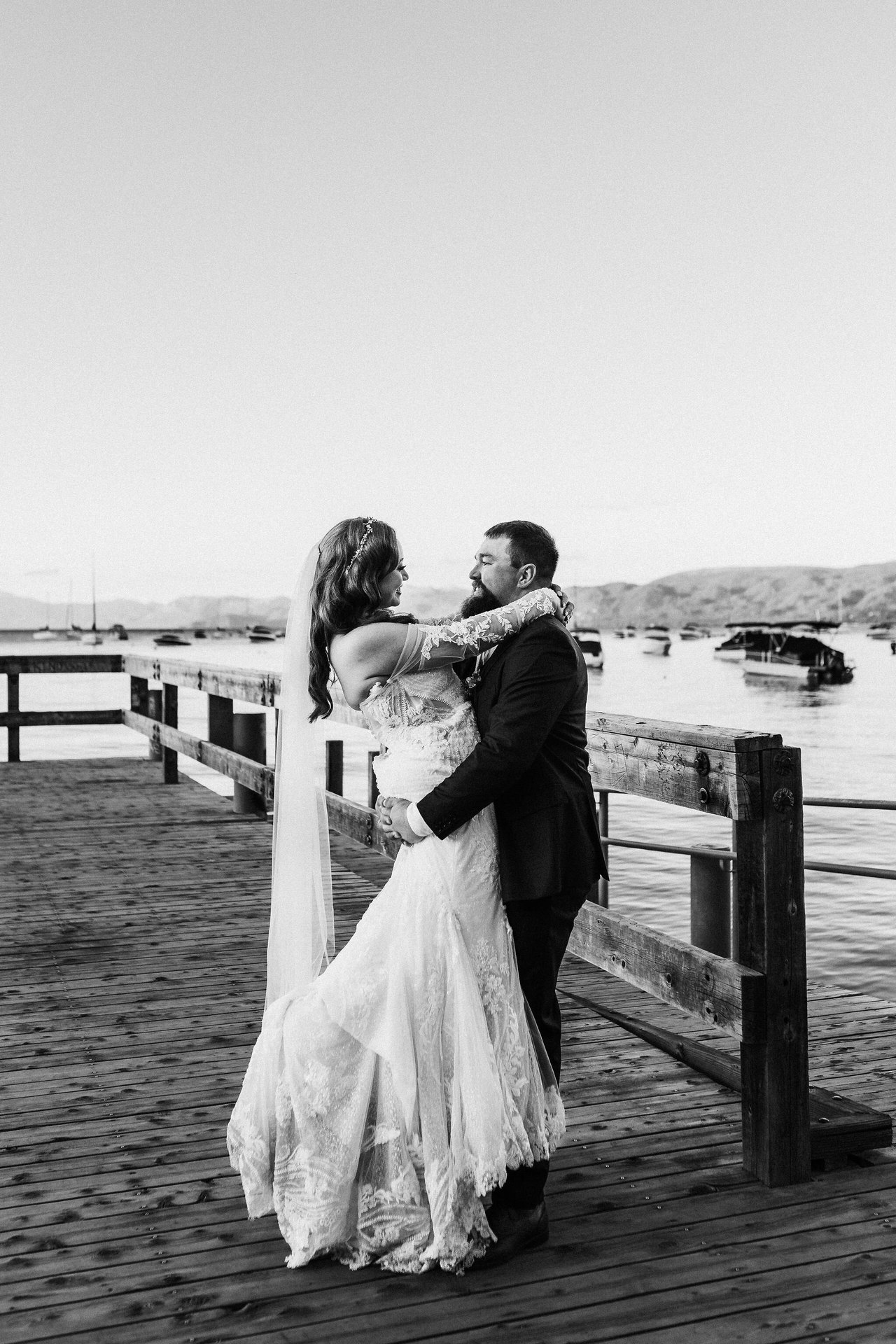 A black and white photo of Remy and Tom embracing on the pier