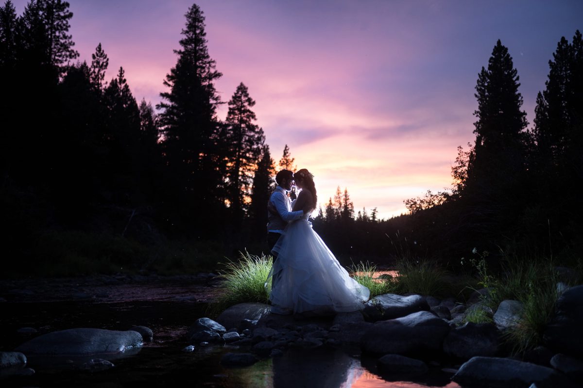 Shannon and Ryan kiss by the river as the rain paints the sunset purple at Twenty Mile House