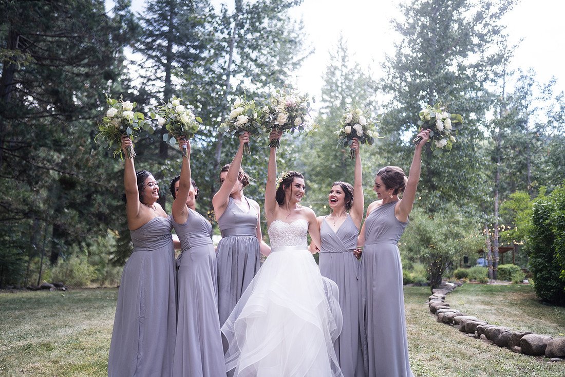 Shannon and her bridesmaids raise their bouquets high on the lawn