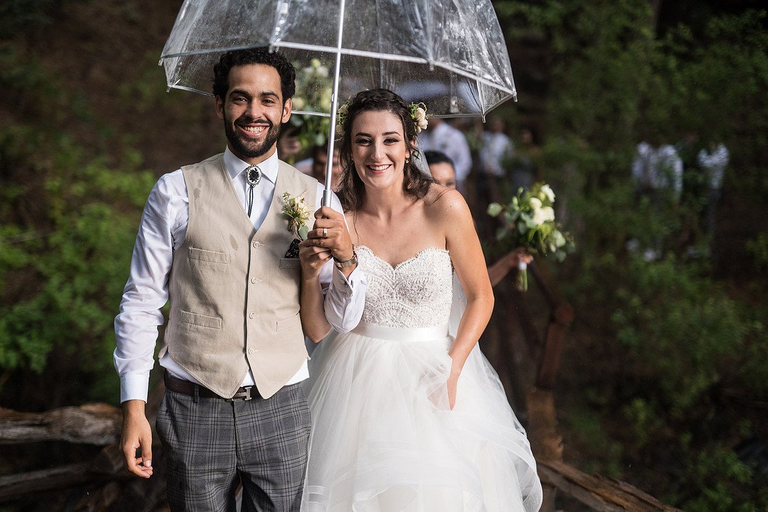Shannon and Ryan laugh under a clear umbrella