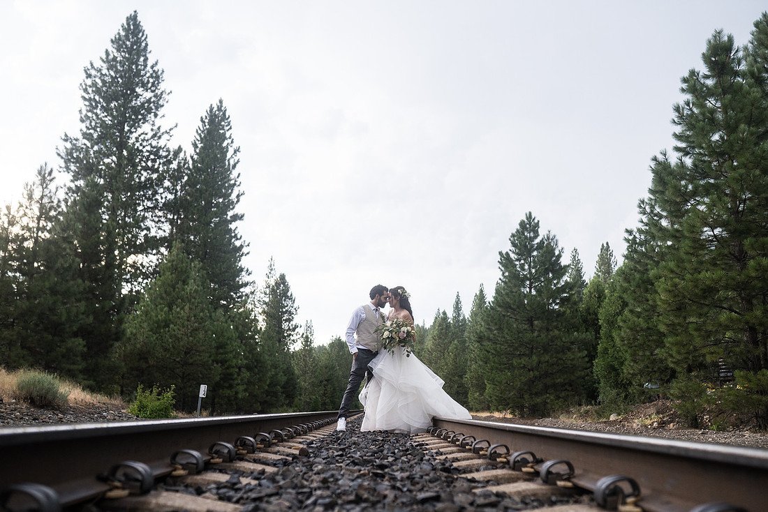Shannon and Ryan kiss far down the railroad tracks between the pines