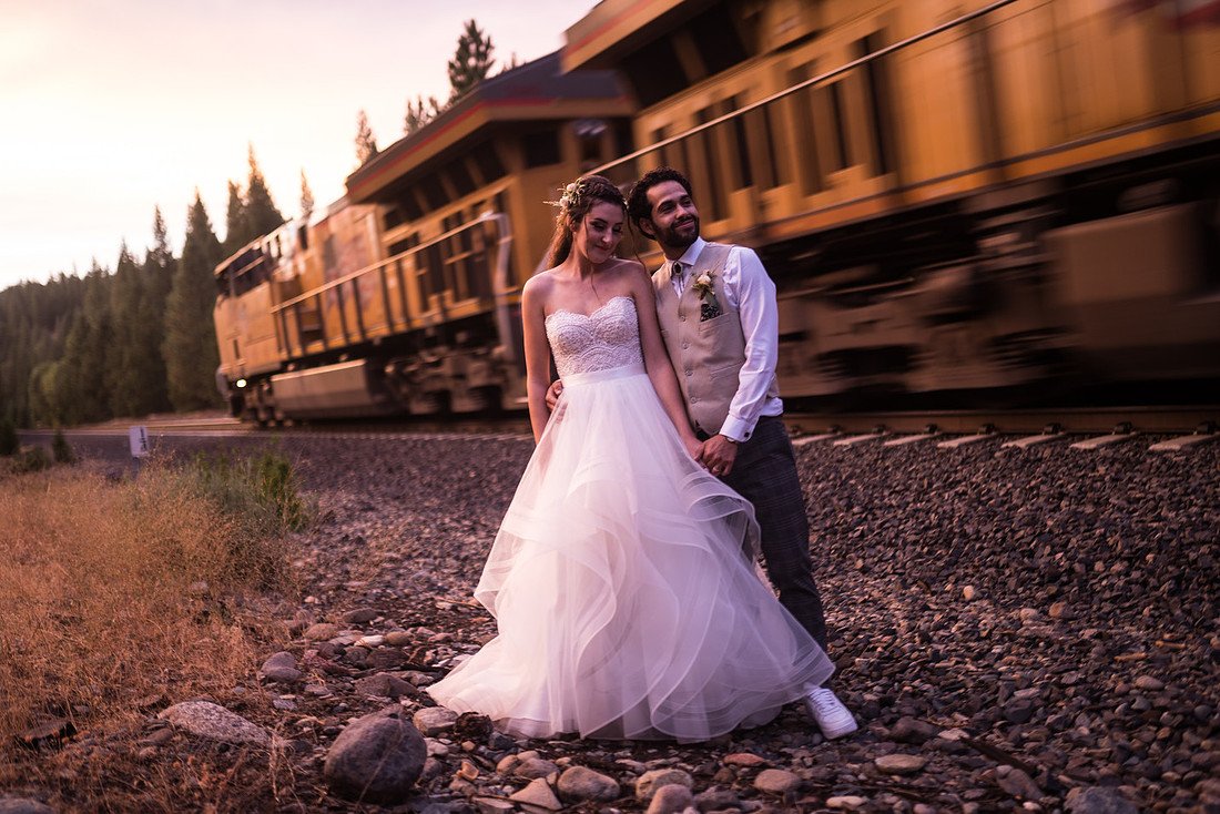 Shannon and Ryan stand by the tracks at sunset as a freight train rushes past