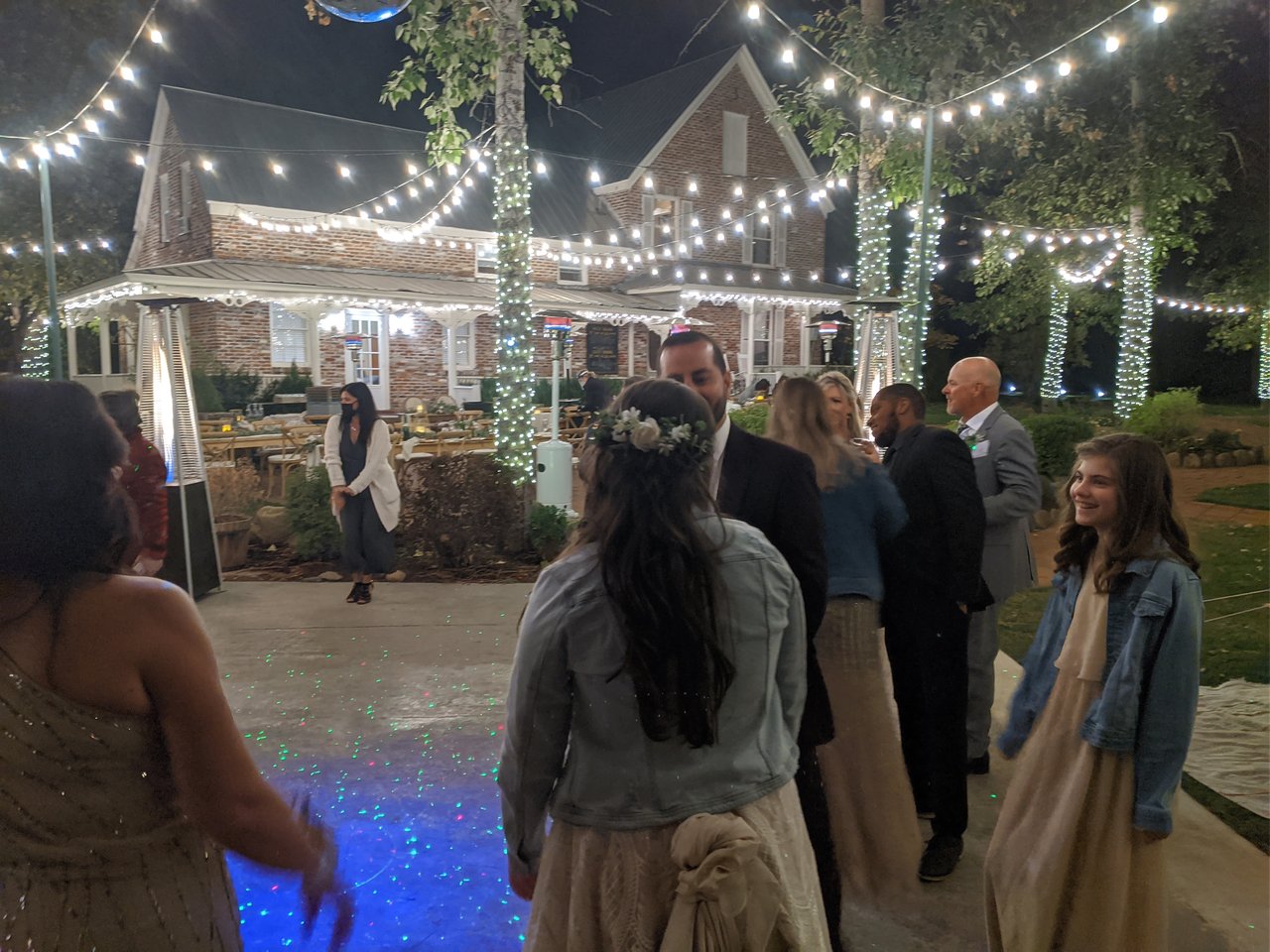 Taylor in her flower crown and denim jacket faces Rob on the dance floor under the string lights at Twenty Mile House