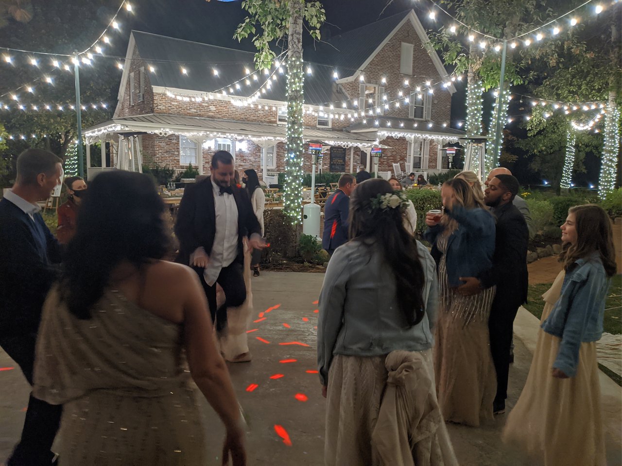 Taylor in her denim jacket watches her guests dance in front of the brick house