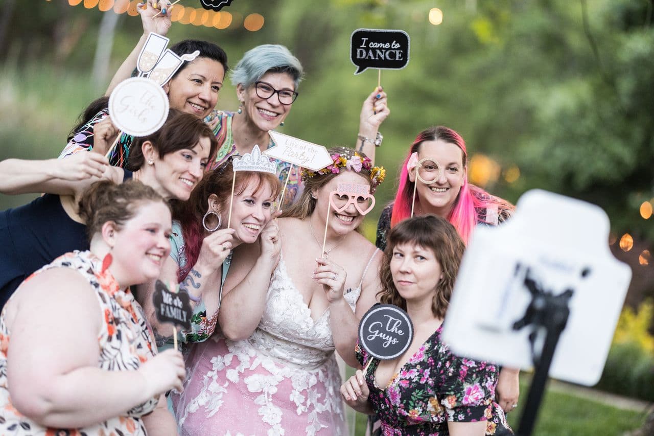 Abney and her wedding guests pose for the photo booth holding props